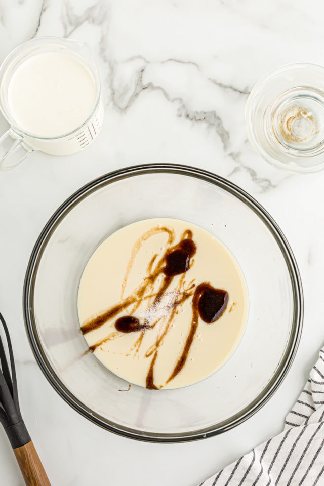 Overhead view of vanilla added to condensed milk and salt in bowl