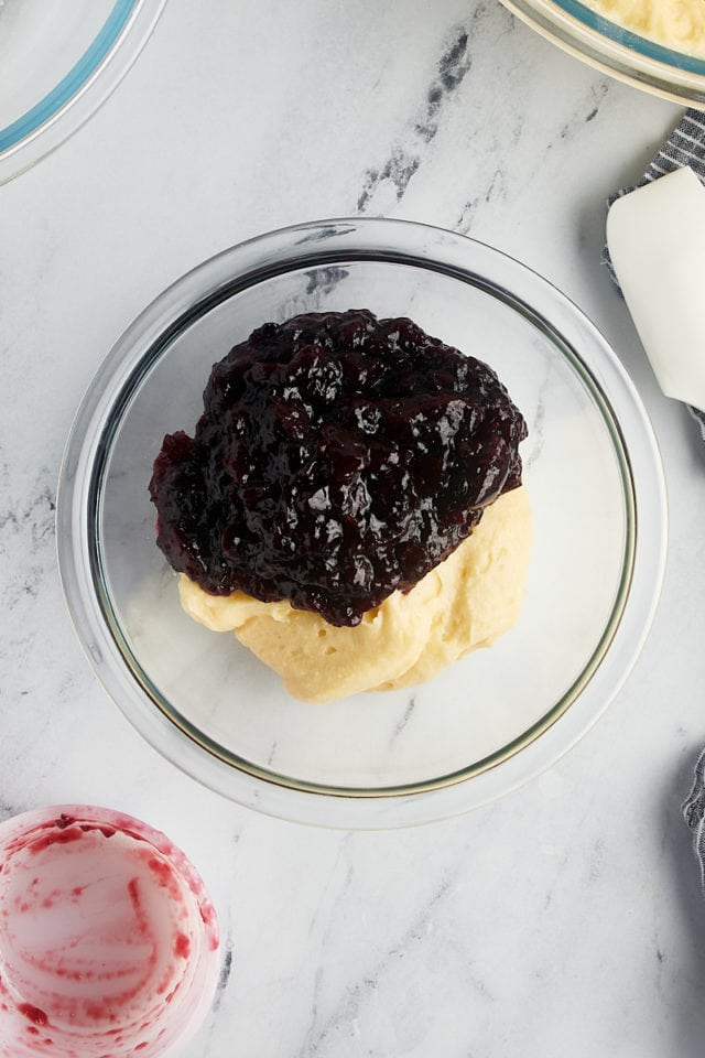 overhead view of cake batter and cherry jam in a glass bowl