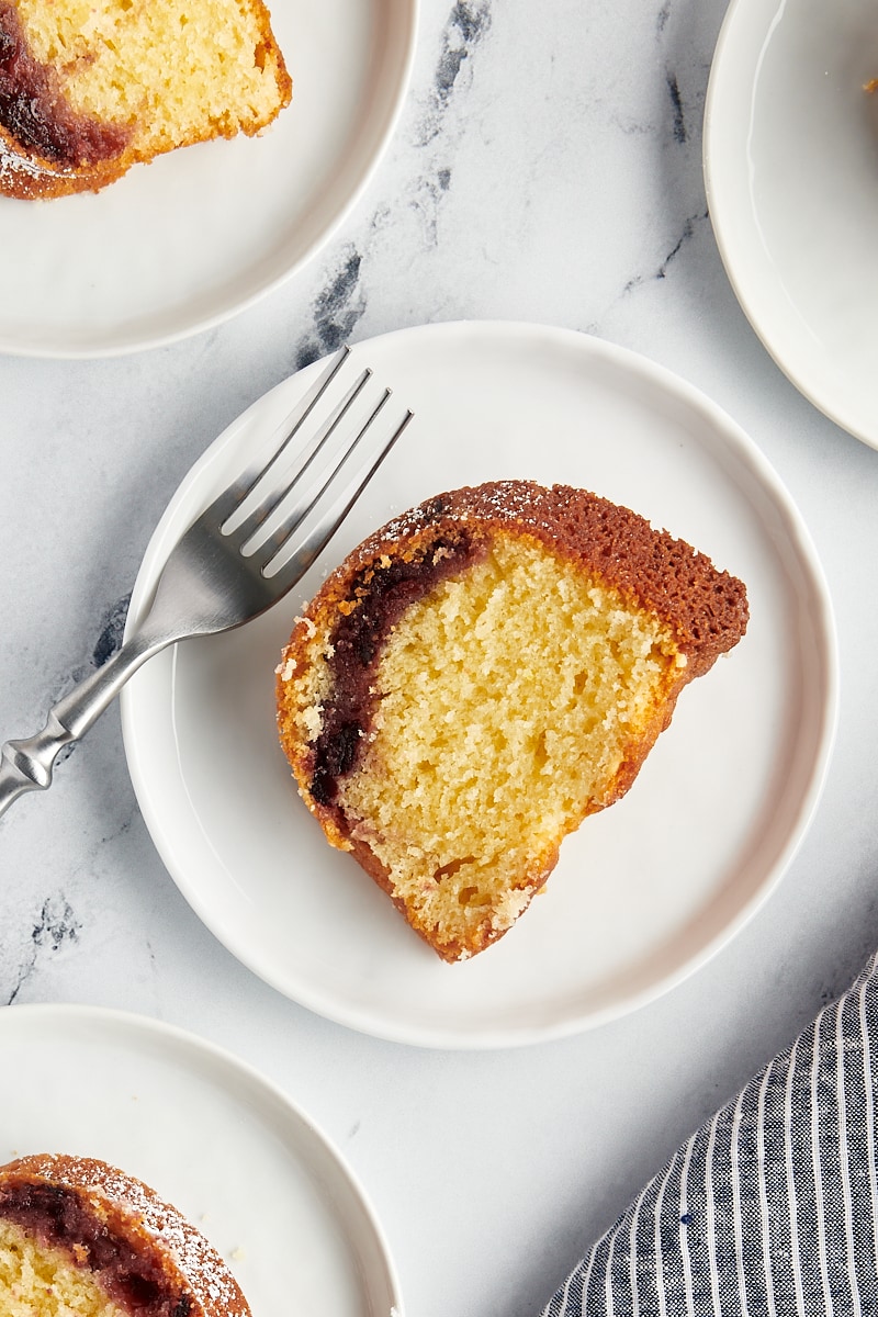 overhead view of a slice of black cherry sour cream coffee cake on a white plate