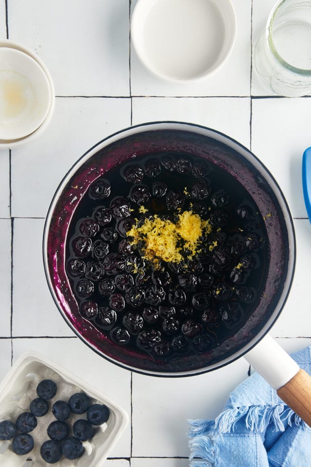 overhead view of vanilla extract and lemon zest added to blueberry compote