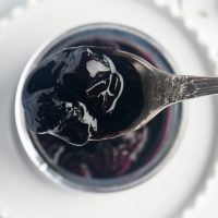 overhead view of a spoonful of blueberry compote over a jar with the remaining compote