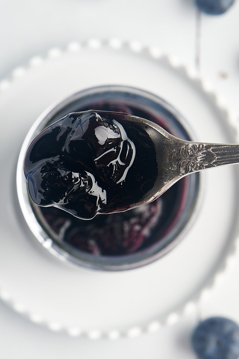 overhead view of a spoonful of blueberry compote over a jar with the remaining compote