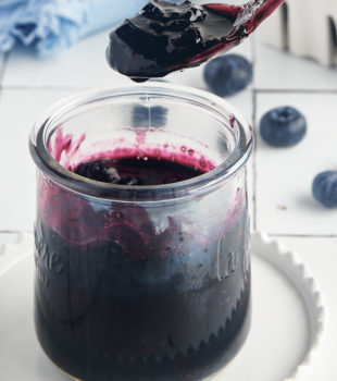 a spoonful of blueberry compote held over a jar of compote