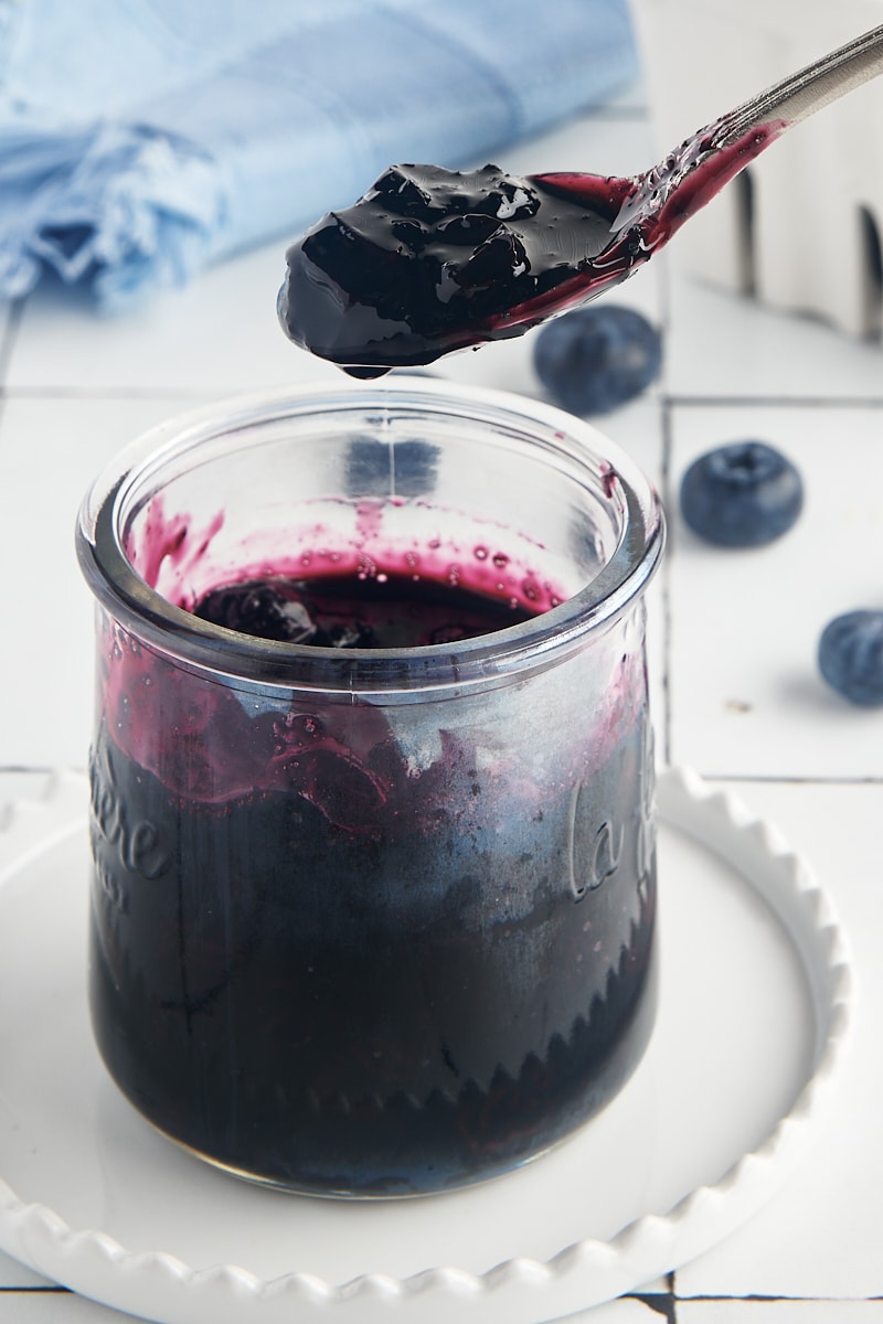 a spoonful of blueberry compote held over a jar of compote
