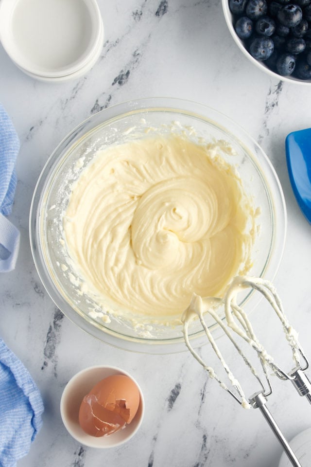 Overhead view of cream cheese layer in mixing bowl with beaters