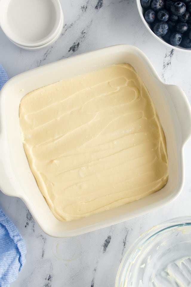 Overhead view of unbaked cream cheese layer in baking dish