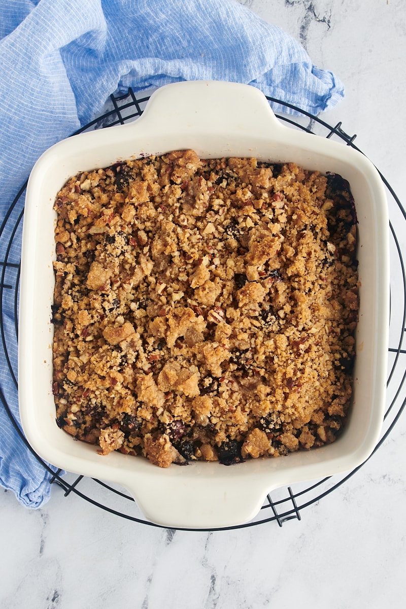 Overhead view of blueberry crisp in baking dish set on round cooling rack