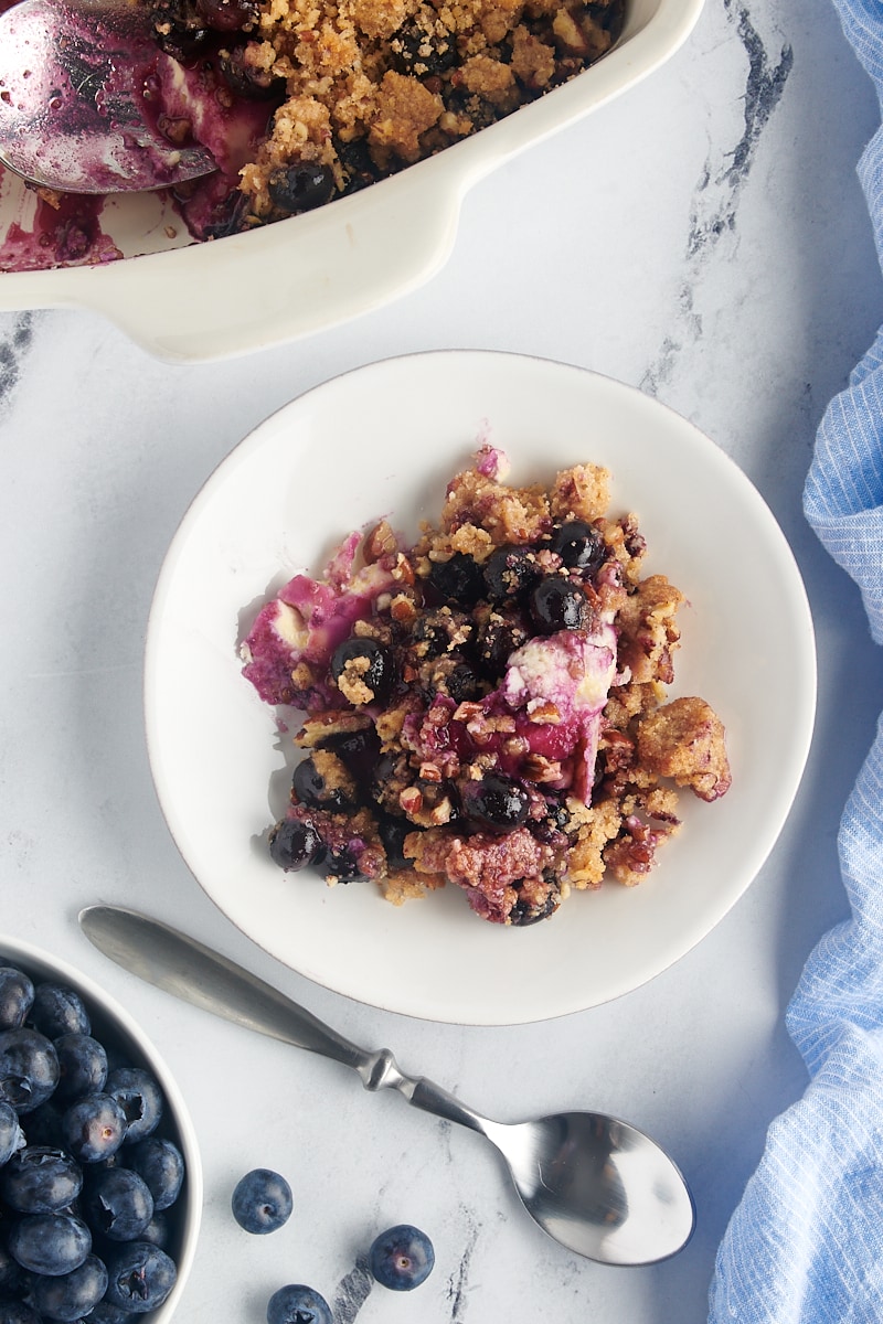 Overhead view of blueberry crisp on plate set next to spoon