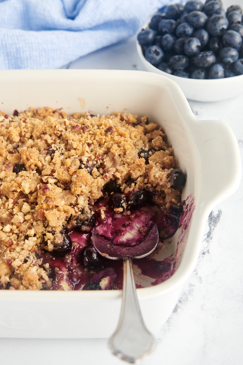 Baking dish of blueberry crisp with portion removed