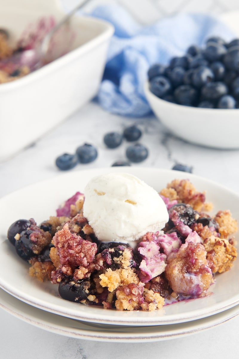 Blueberry crisp on plate with scoop of vanilla ice cream on top