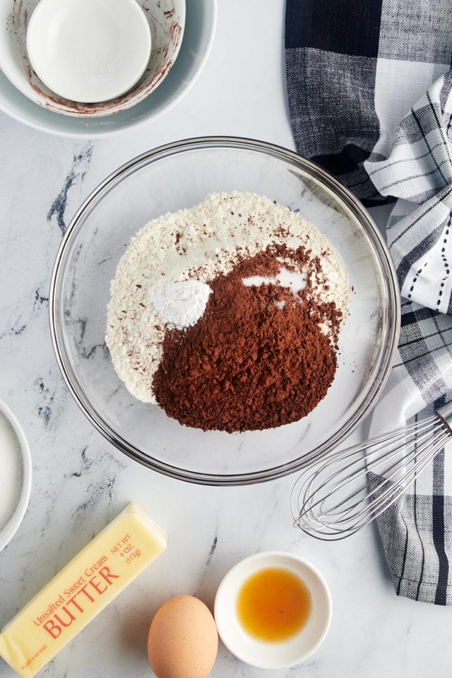 overhead view of flour, cocoa powder, baking powder, and salt in a glass mixing bowl