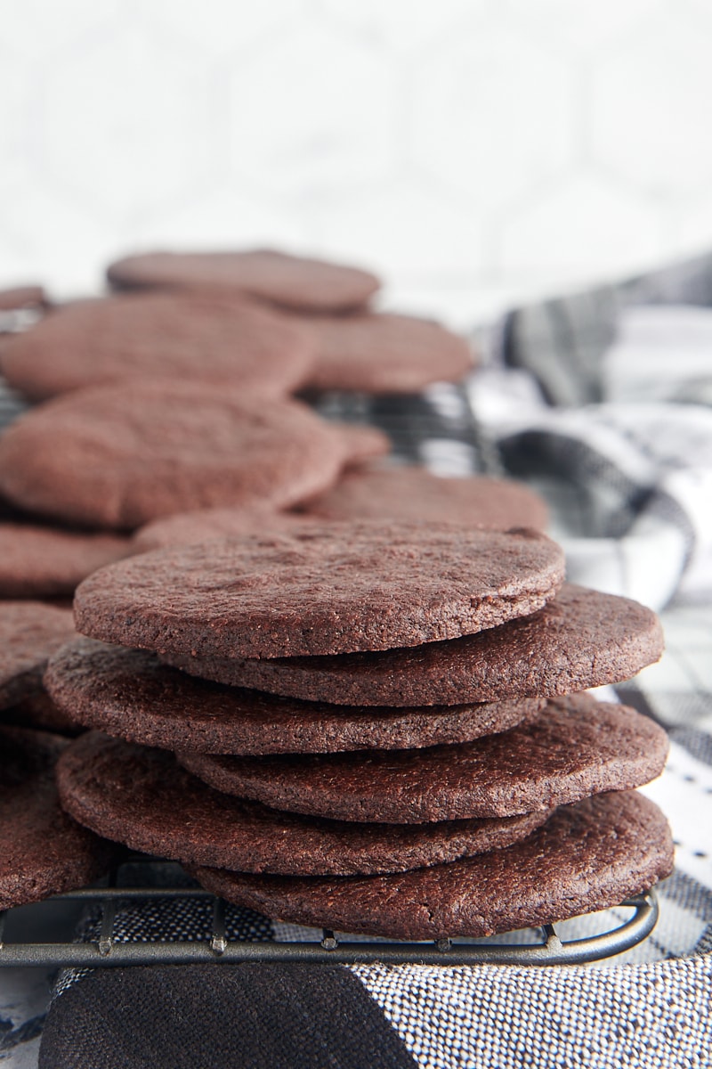 stack of six chocolate wafer cookies on a wire rack along with more cookies