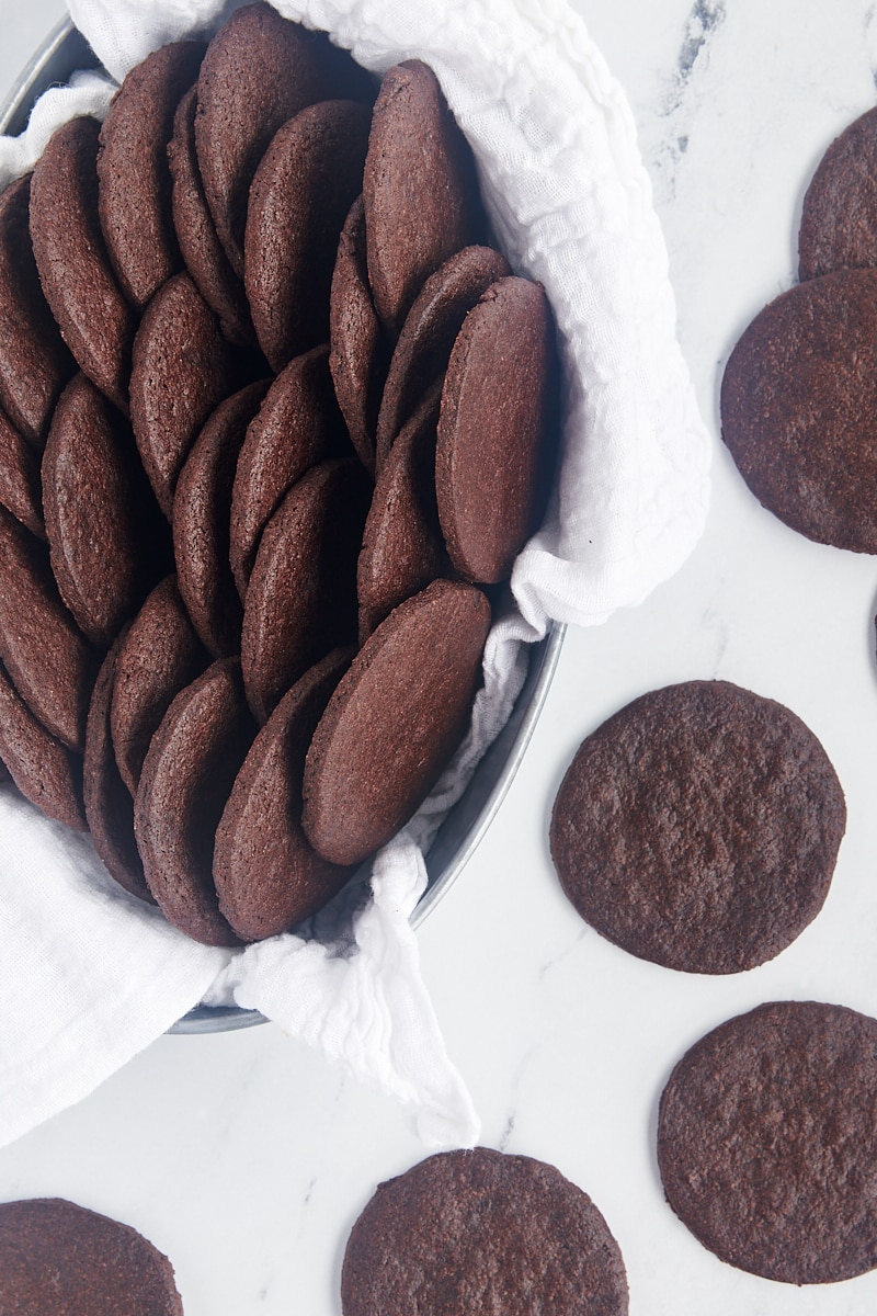 overhead view of chocolate wafer cookies in a towel-lined basket with more cookies alongside