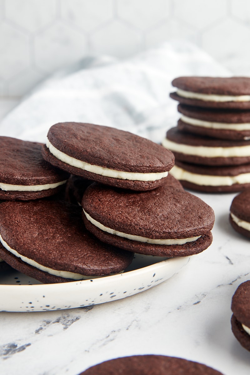 Homemade Oreos on a white plate with more stacked behind