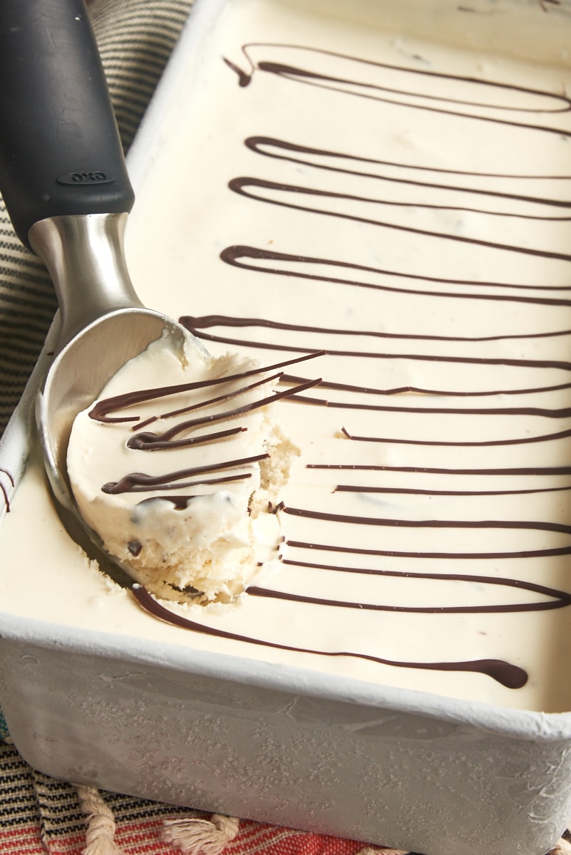 a container of stracciatella ice cream with a scoop on an ice cream disher on top
