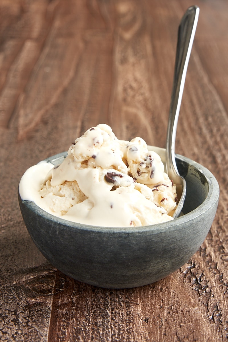 Partially melted stracciatella ice cream in gray bowl with spoon