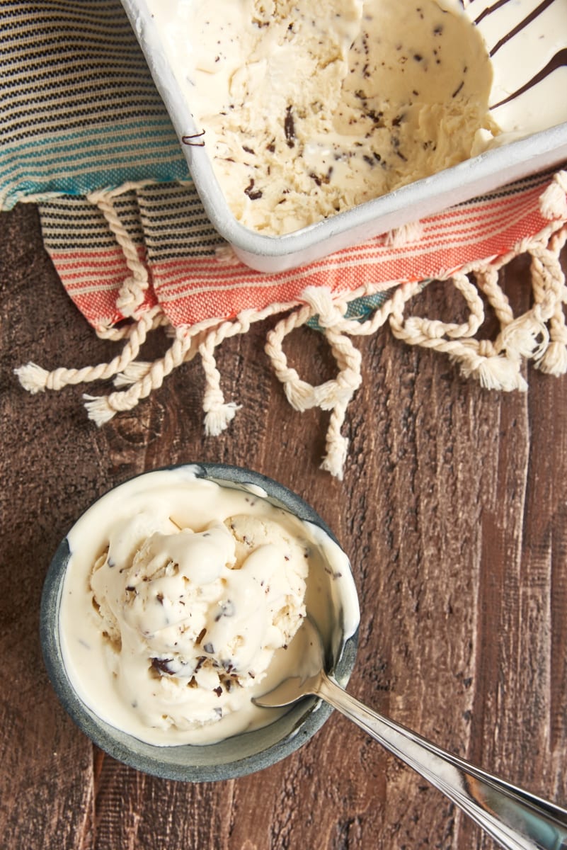 Overhead view of no-churn stracciatella ice cream in bowl with spoon next to pan of ice cream