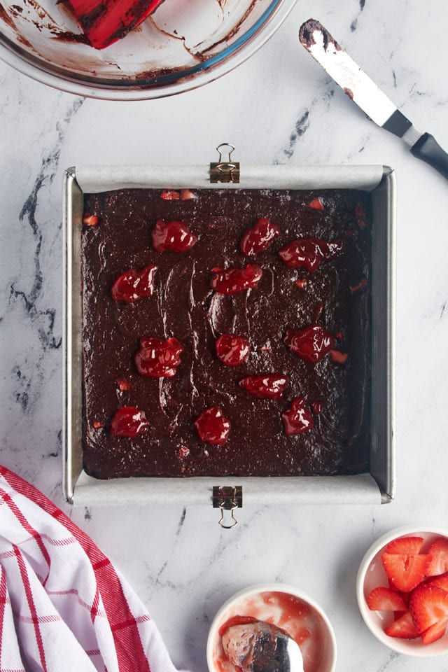 Overhead view of strawberry jam dropped over brownie batter