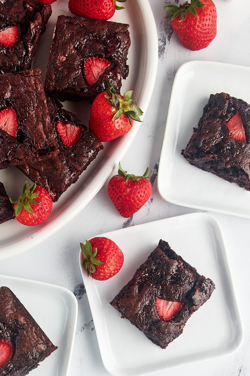 Overhead view of strawberry brownies on 3 square plates and platter