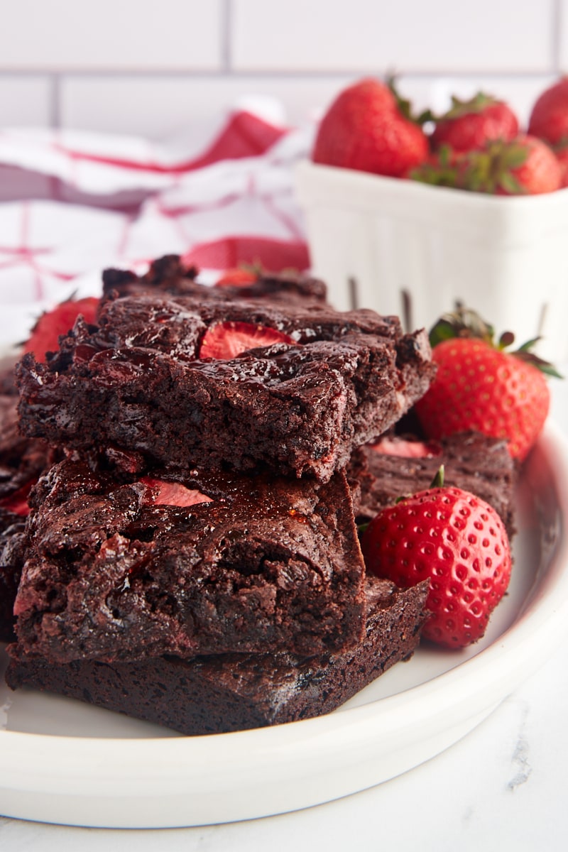 Stack of strawberry brownies on plate with fresh strawberries
