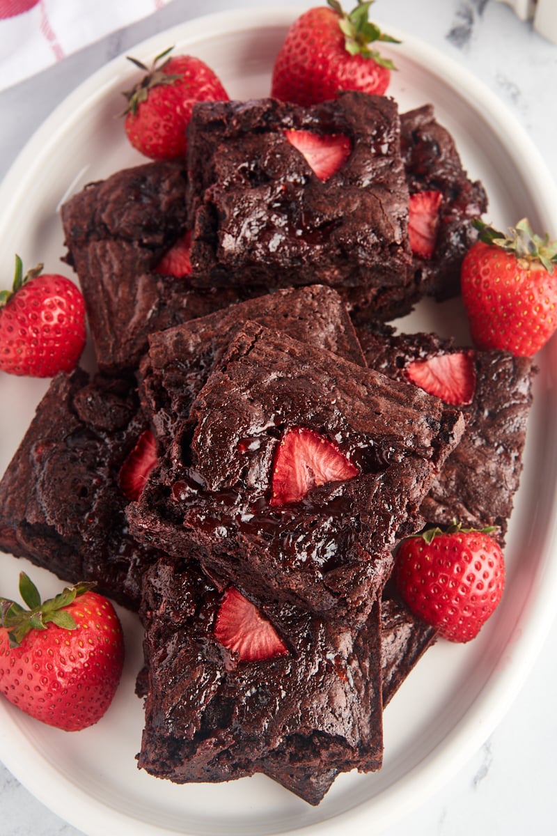 Overhead view of strawberry brownies on platter with fresh strawberries