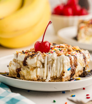 Banana split cake on plate topped with cherry