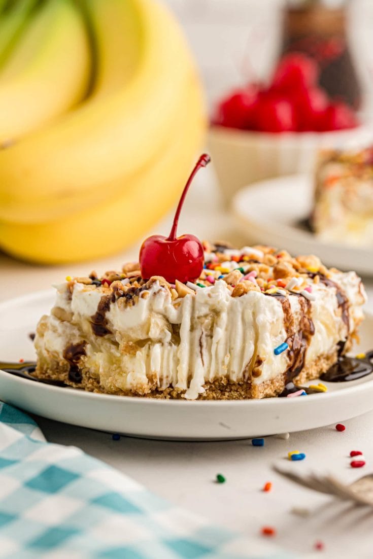Banana split cake on plate topped with cherry