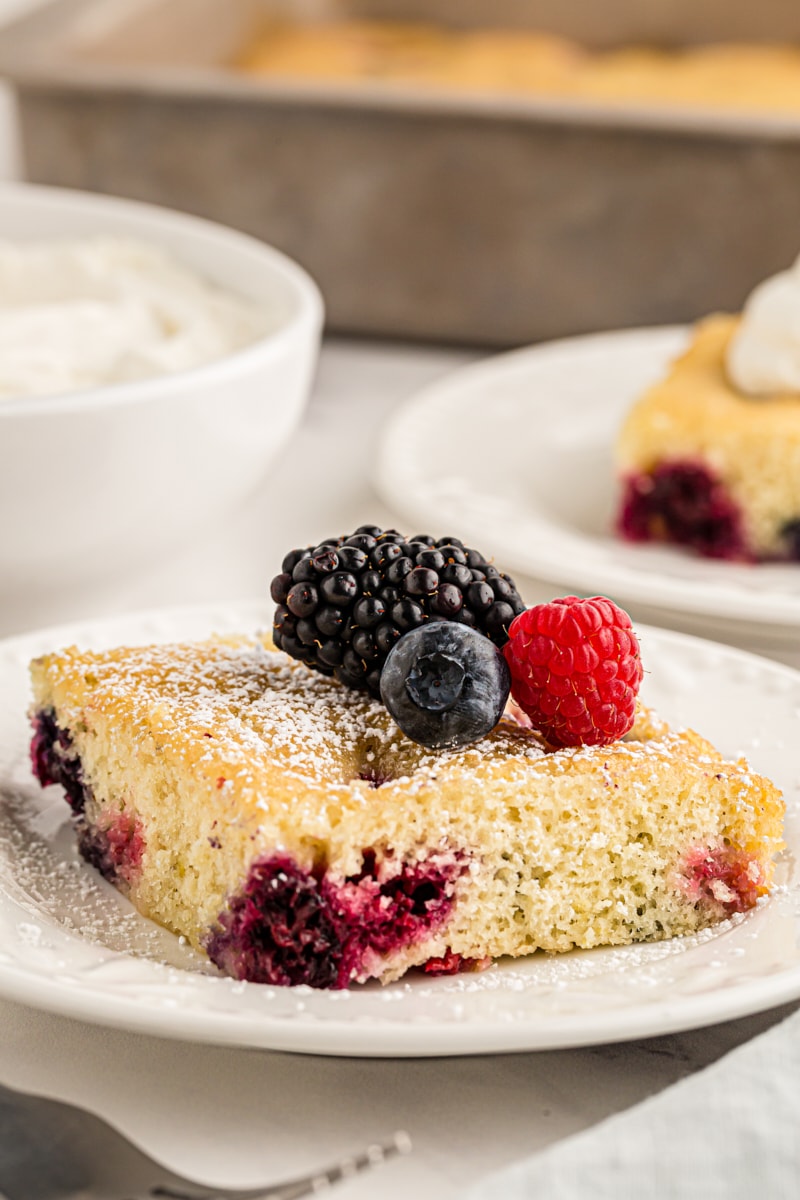 a slice of berry pudding cake topped with fresh berries