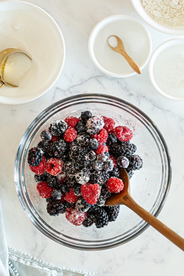 overhead view of berries mixed with sugar in a glass mixing bowl