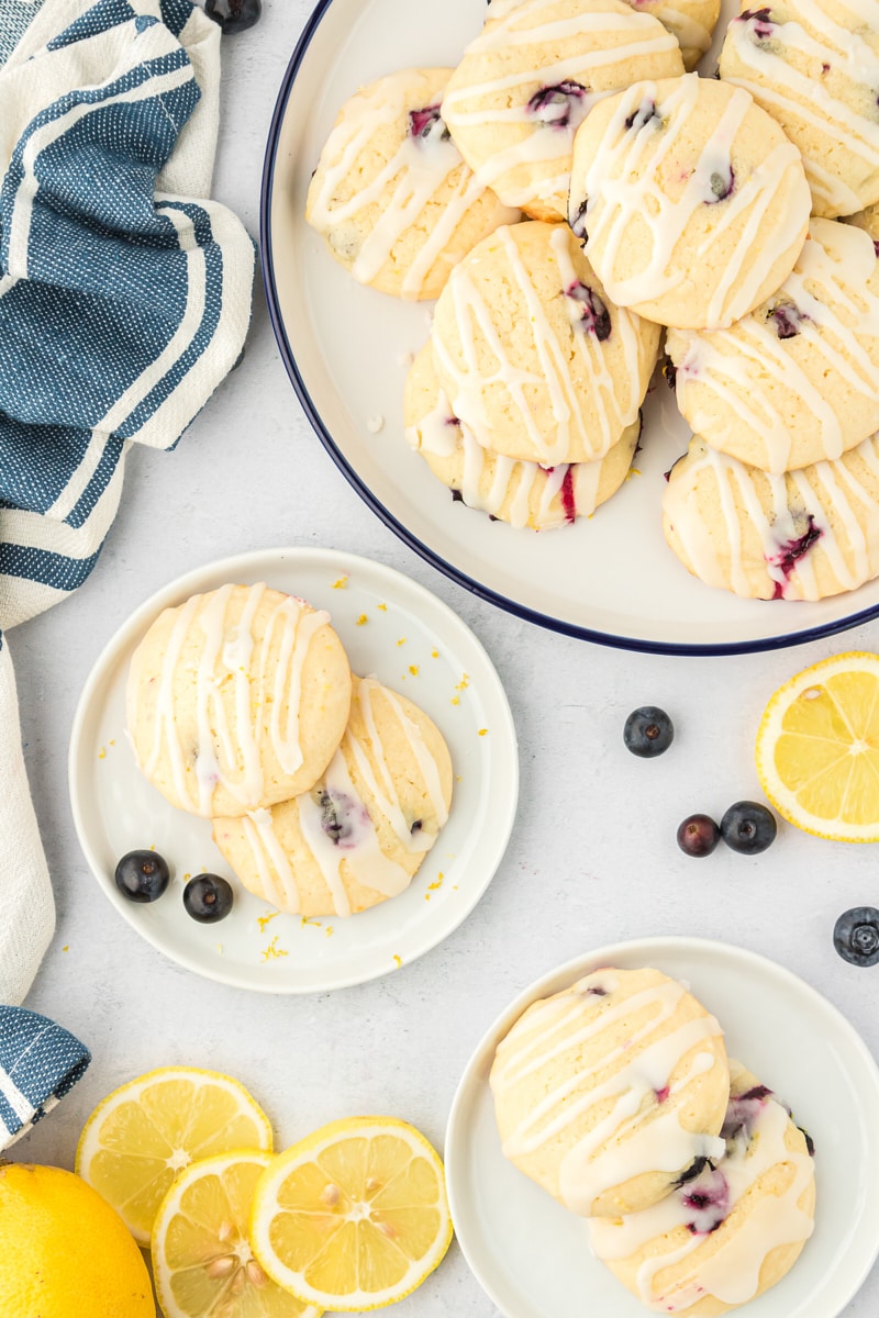 overhead view of lemon blueberry cookies on small white plates and on a large white serving plate