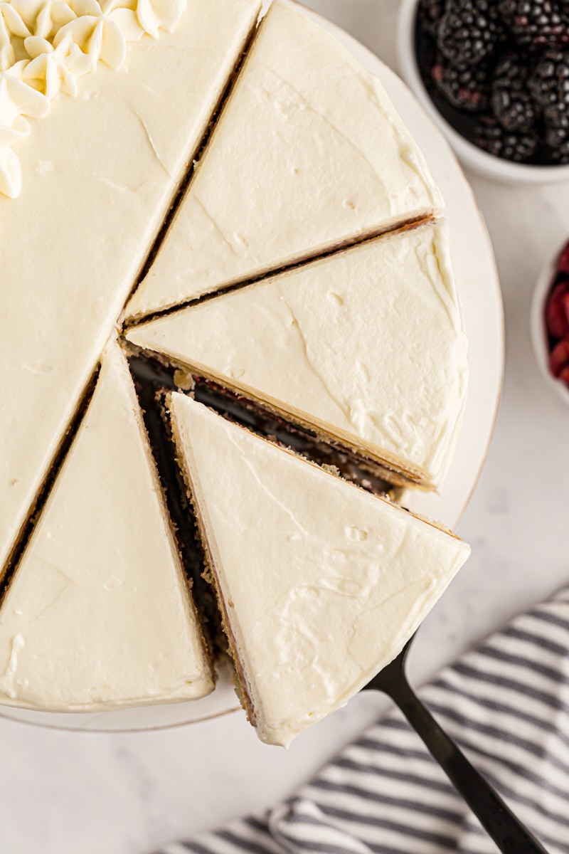 Overhead view of sliced chantilly cake with slice being removed