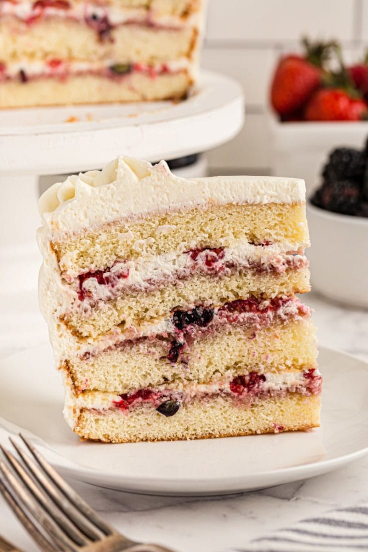 Side view of chantilly cake slice on plate, showing 4 cake layers