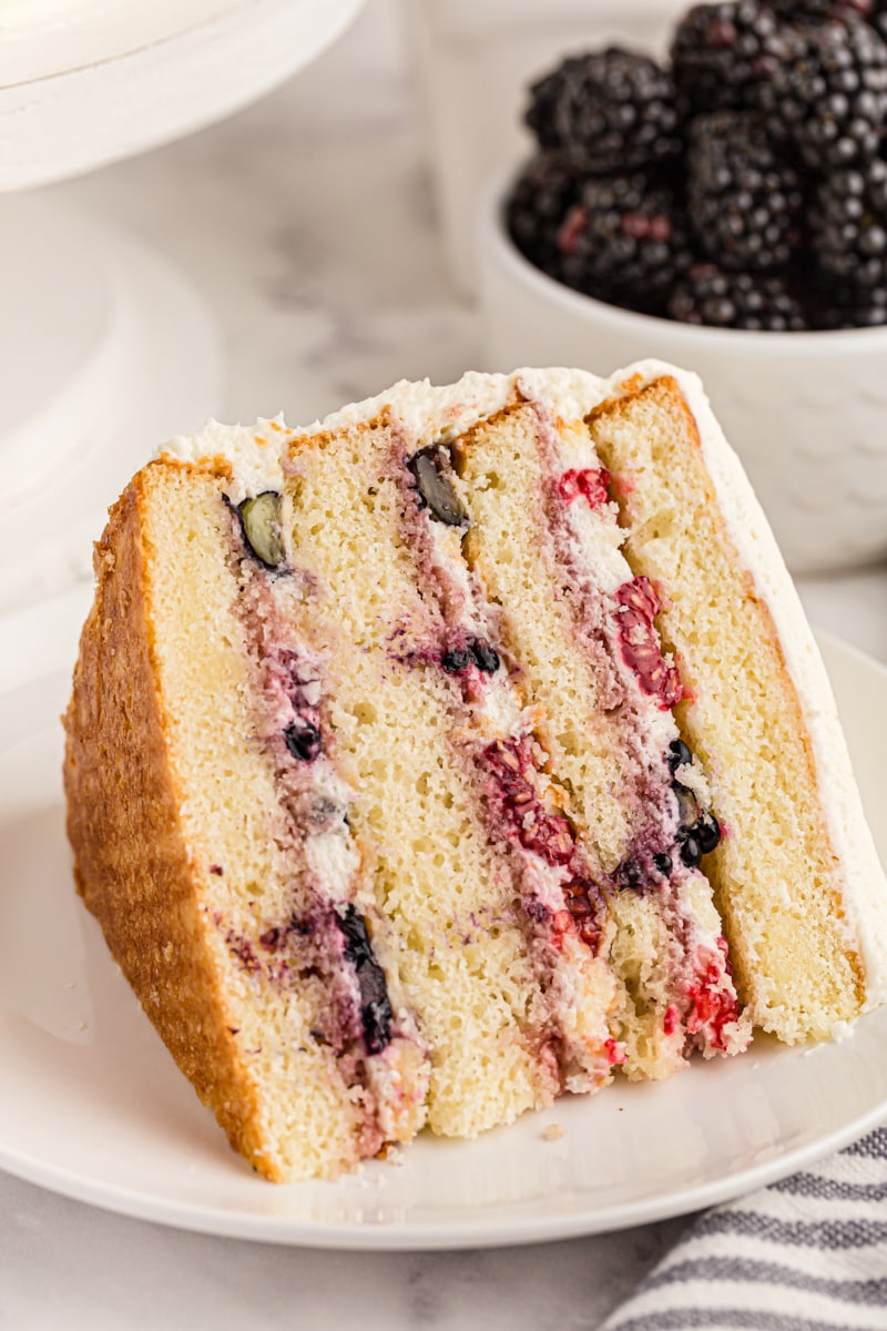 Chantilly cake slice on plate, with layers of whipped frosting and fresh berries