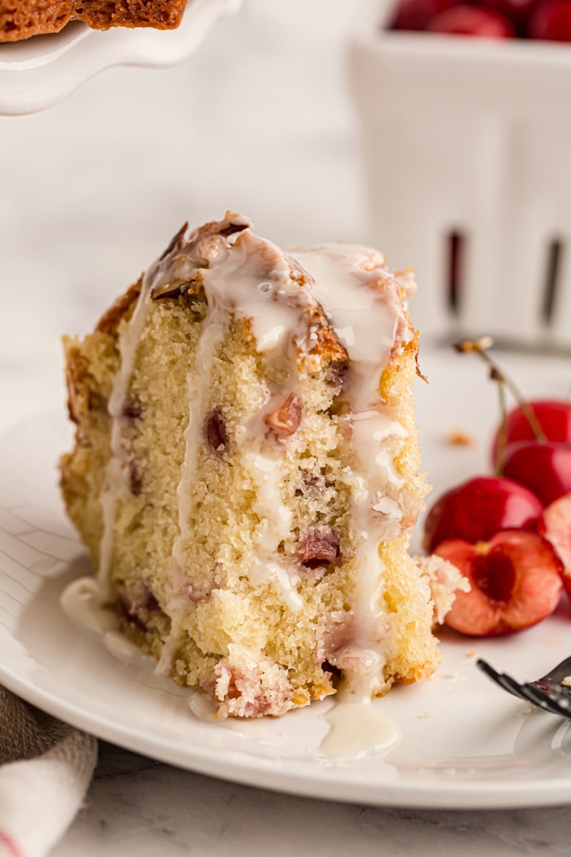 Slice of cherry-vanilla yogurt cake on plate with fresh cherries