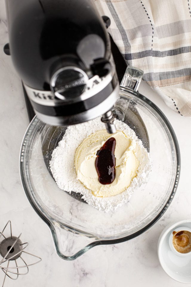 overhead view of mascarpone, confectioners' sugar, and vanilla bean paste in the bowl of a stand mixer
