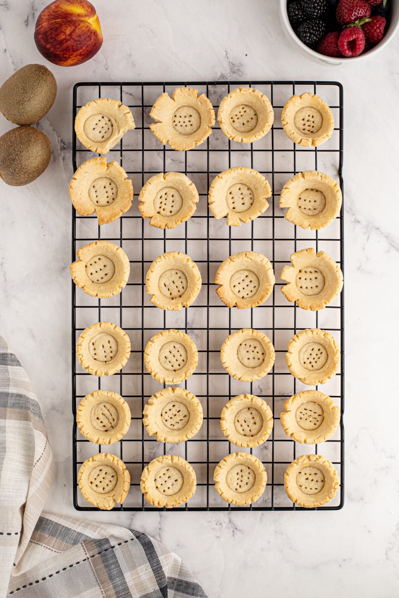 overhead view of baked mini tart shells on a wire rack