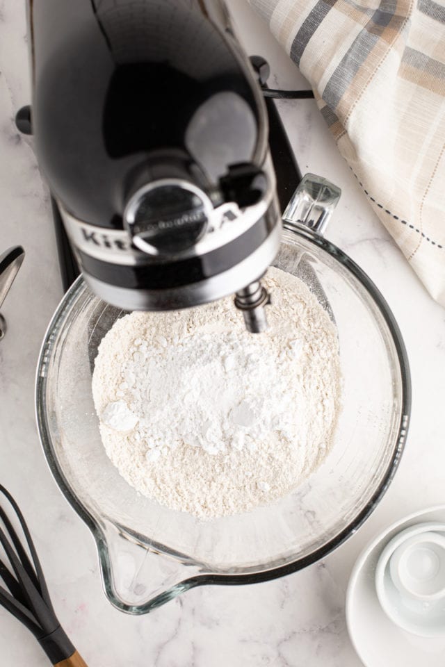 overhead view of flour, confectioners' sugar, and salt in the bowl of stand mixer