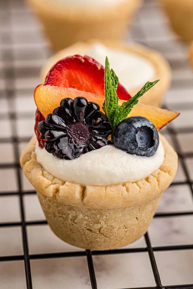 a mini fruit tart on a wire rack with more tarts behind