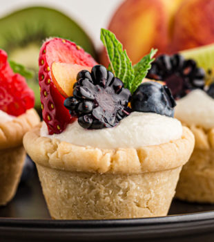 close-up of a mini fruit tart surrounded by more tarts and fresh fruit