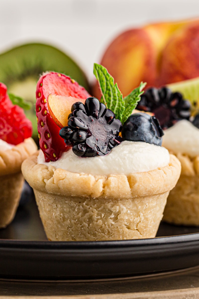 close-up of a mini fruit tart surrounded by more tarts and fresh fruit