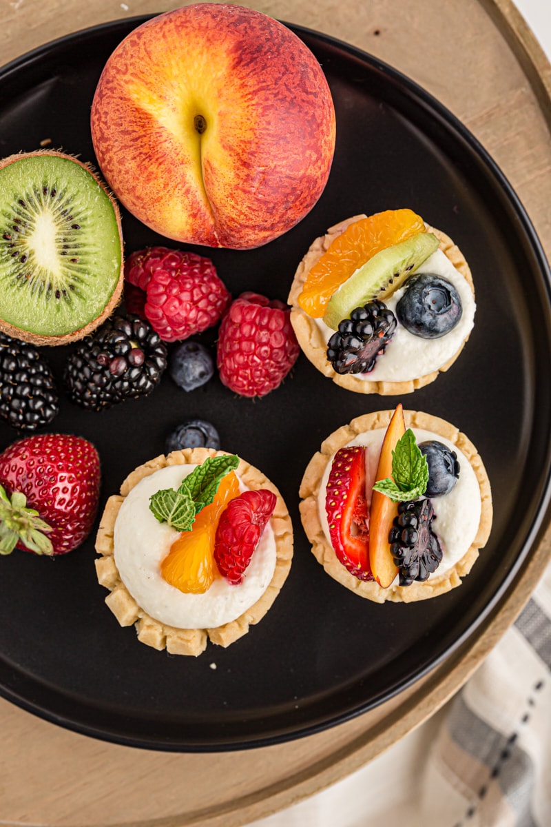 overhead view of mini fruit tarts on a black serving tray