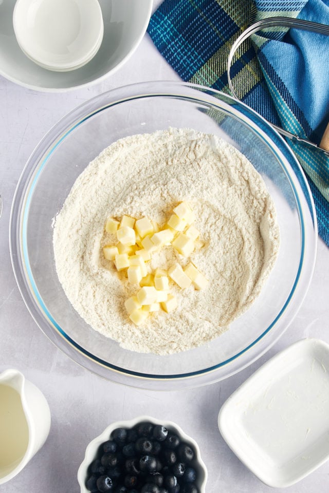 Overhead view of butter cubes in mixing bowl of dry ingredients