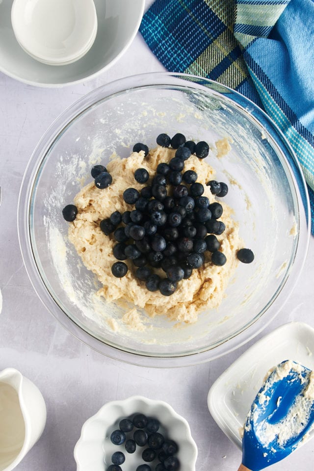 Overhead view of blueberries added to bowl of dough