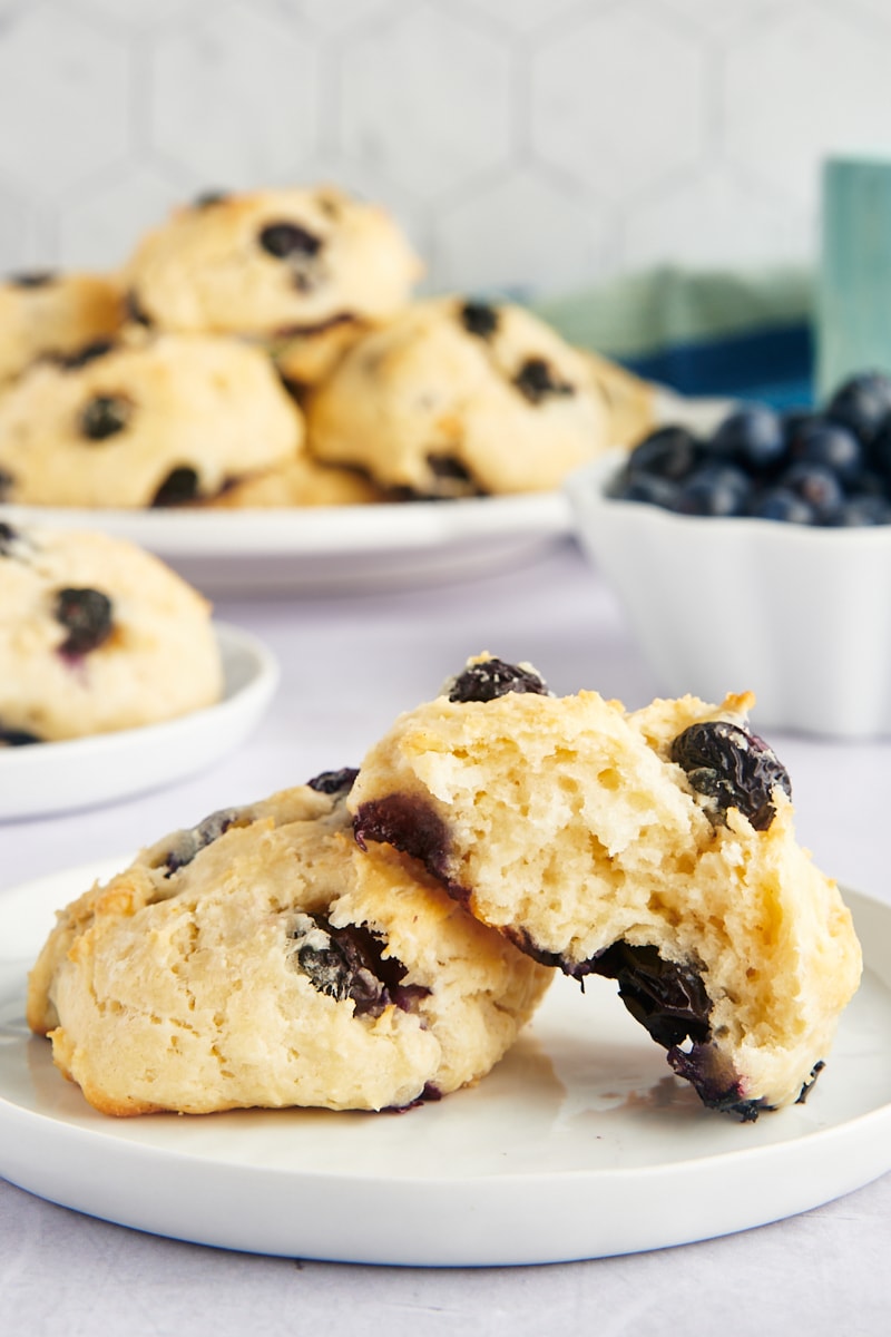 Two blueberry biscuits on plate, with one bitten into to show light texture