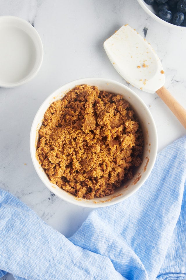 overhead view of mixed graham cracker crumb crust in a white mixing bowl