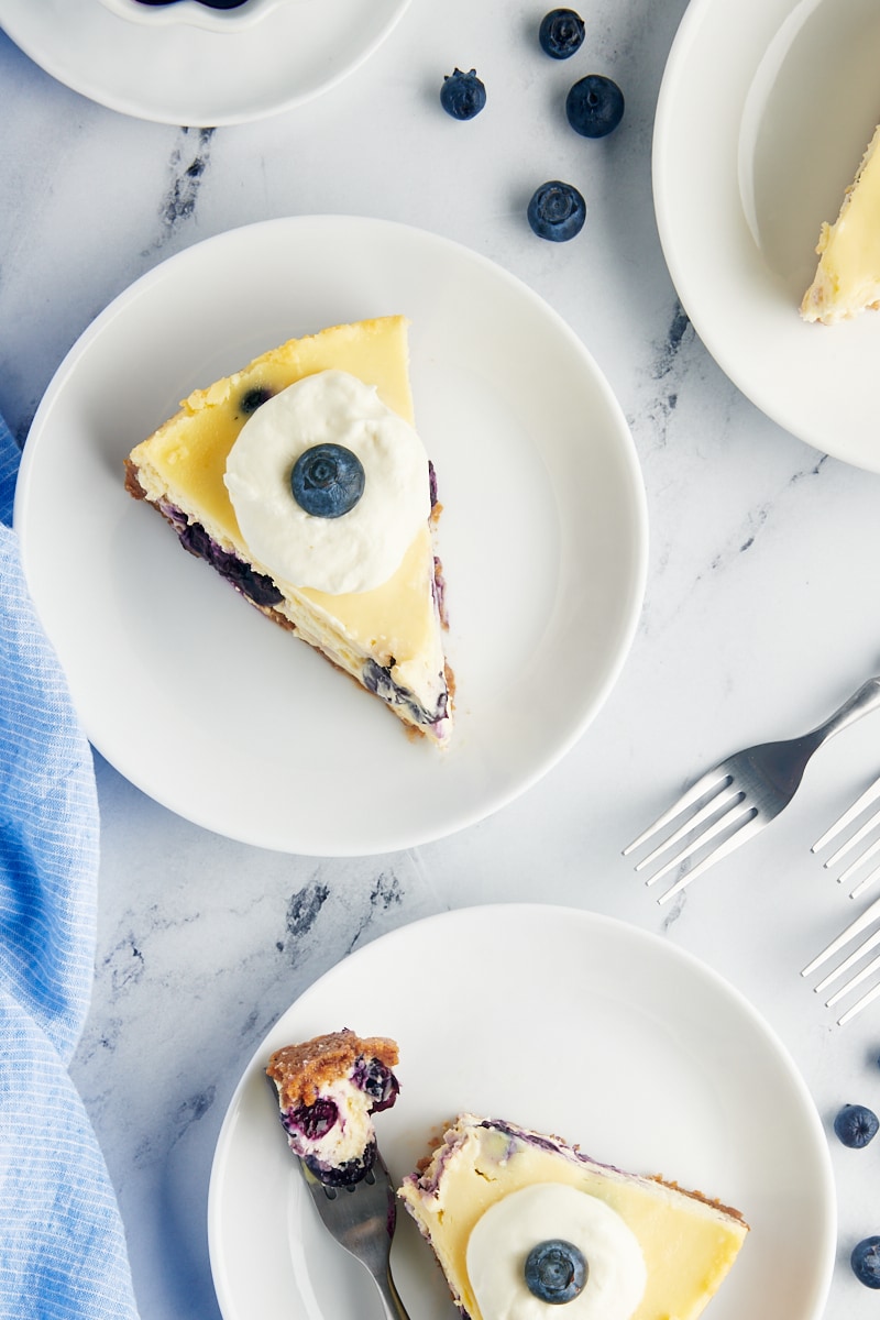 overhead view of slices of blueberry cheesecake on white plates