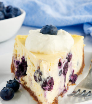 a close up of a slice of blueberry cheesecake on a white plate