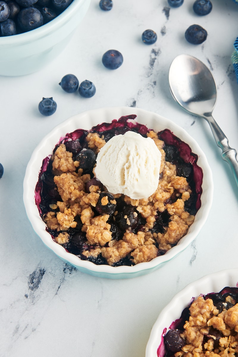 Personal-sized blueberry crumble topped with scoop of vanilla ice cream