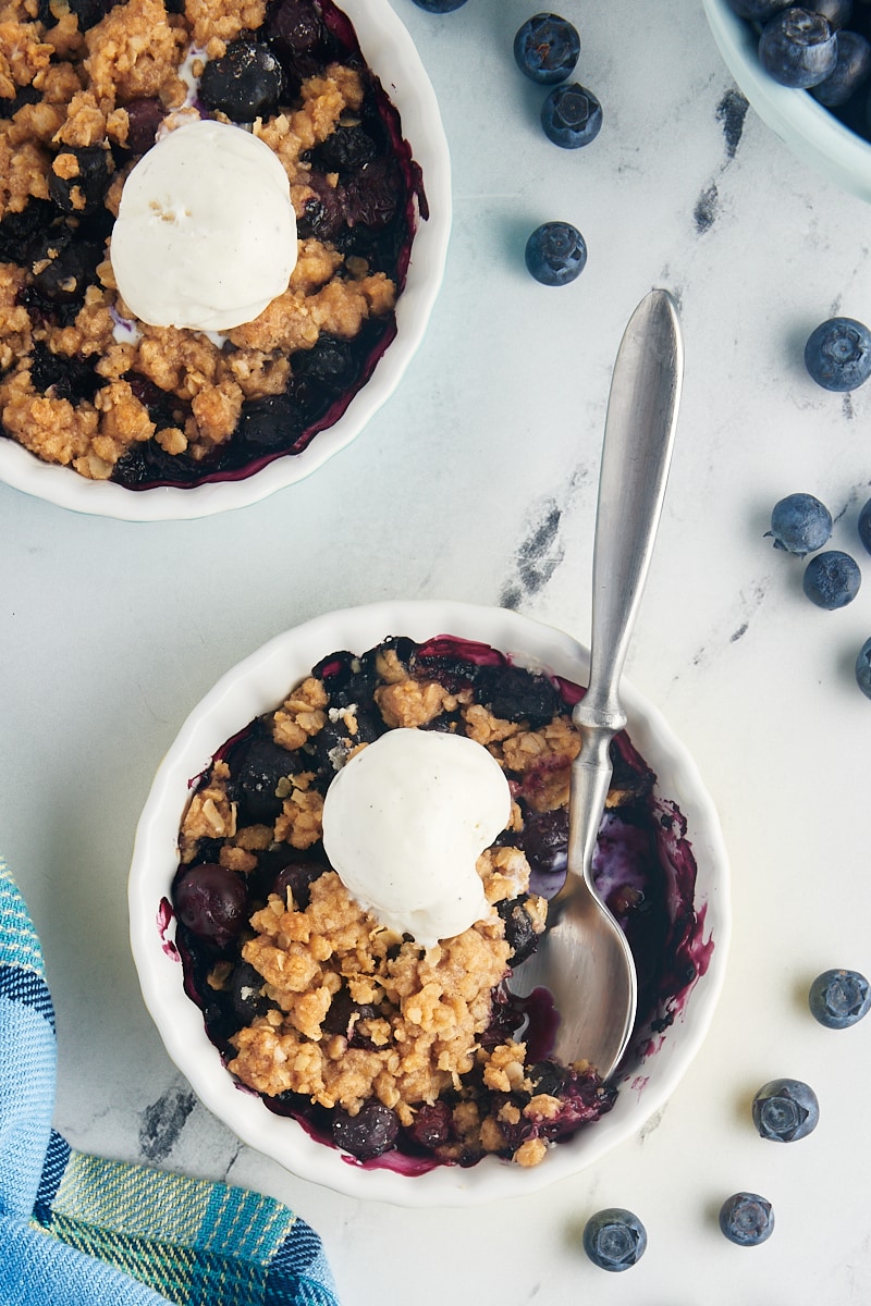 Overhead view of two blueberry crumbles topped with vanilla ice cream