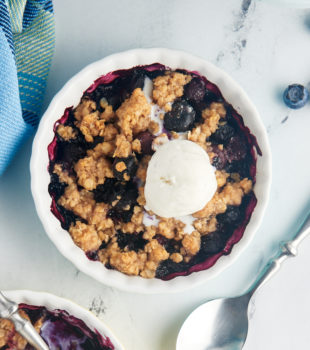 Overhead view of blueberry crumble topped with scoop of vanilla ice cream